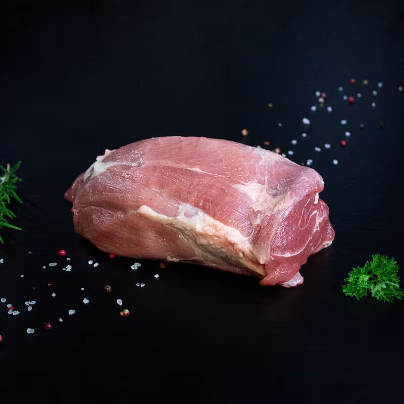 Roher Wildschweinbraten aus der Keule mit Kräutern und Gewürzen auf dunklem Untergrund