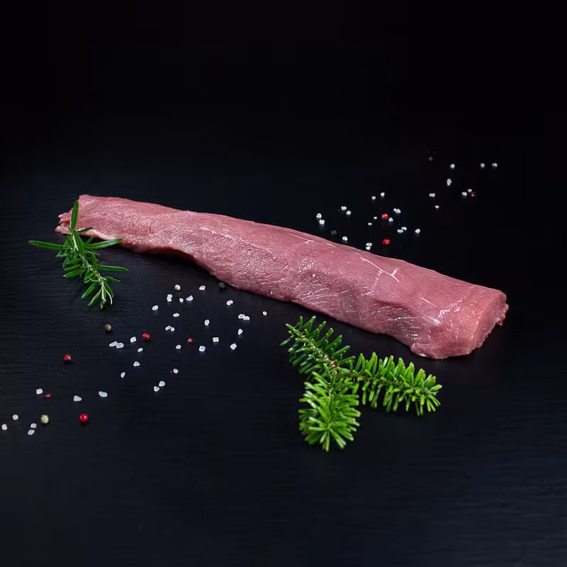 Roher parierter Wildschweinrücken ohne Knochen mit Pfeffer, Salz und Chili auf dunklem Untergrund