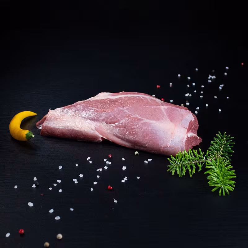 Roher Wildschweinbraten aus der Schulter mit Kräutern und Gewürzen auf dunklem Untergrund