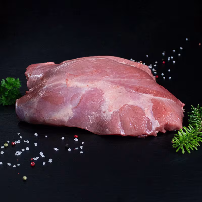 Rohe Frischlingskeule ohne Knochen mit Pfeffer, Salz und Chili auf dunklem Untergrund