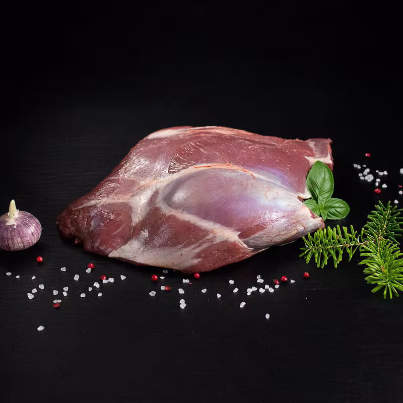 Rohe Rehkeule ohne Knochen mit Pfeffer, Salz und Chili auf dunklem Untergrund