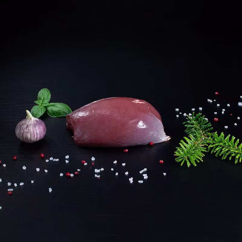 Roher Rehbraten aus der Keule mit Kräutern und Gewürzen auf dunklem Untergrund