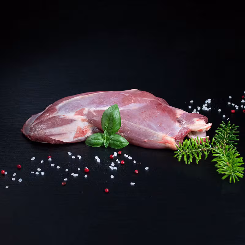 Rohe Rehschulter mit Knochen, Pfeffer, Salz und Chili auf dunklem Untergrund