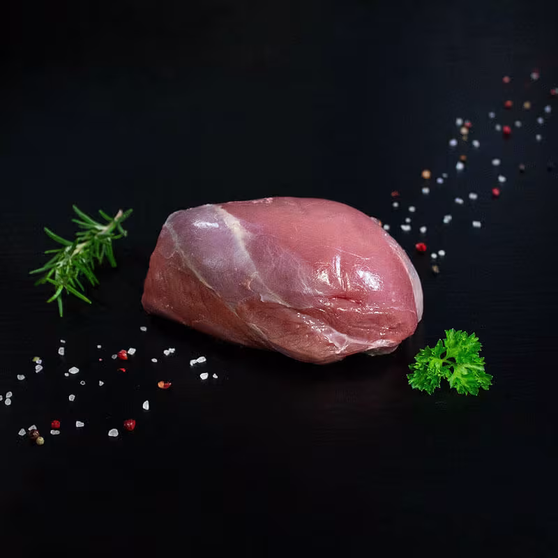 Roher Hirschkalbsbraten aus der Keule mit Kräutern und Gewürzen auf dunklem Untergrund