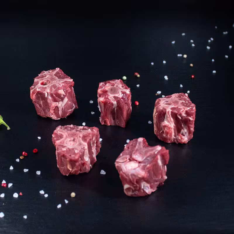 Rohe Rehknochen für den Wildfond mit Pfeffer, Salz und Chili auf dunklem Untergrund