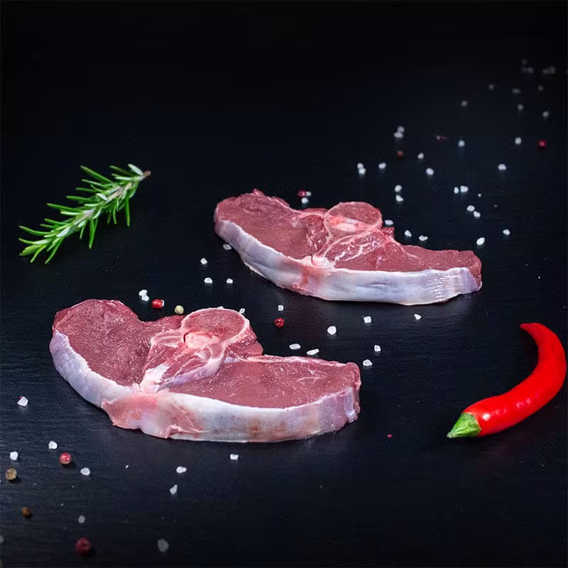 Rohe Hirschkoteletts mit Kräutern und Gewürzen auf dunklem Untergrund