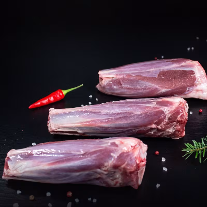 Rohe Wildschweinhaxen mit Kräutern und Gewürzen auf dunklem Untergrund