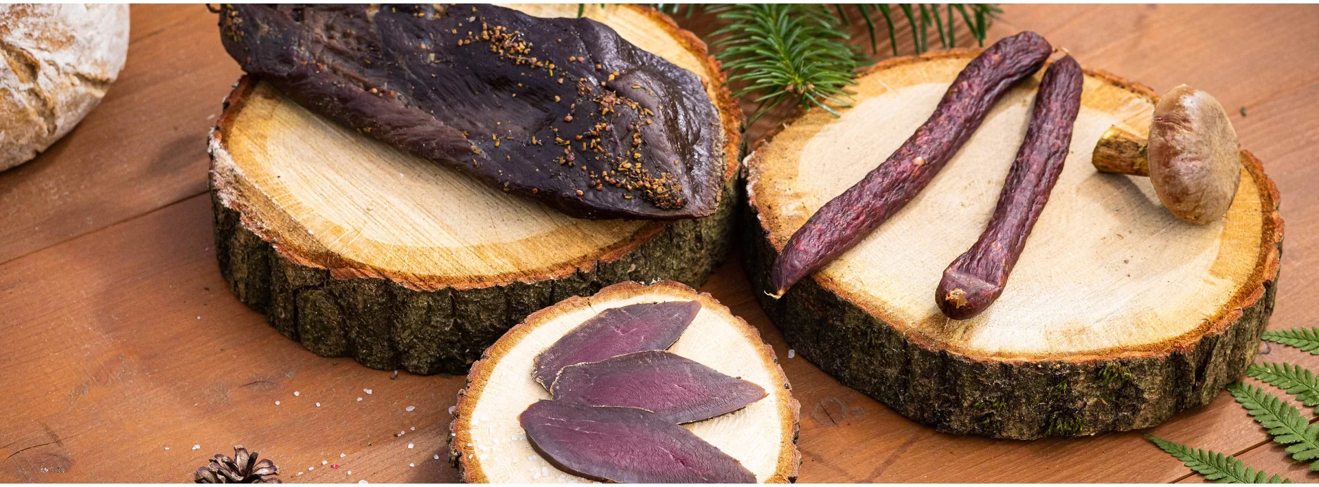 Wildschinken, Wildsalami und Wildwurst auf Baumscheiben im Banner der Kategorie
