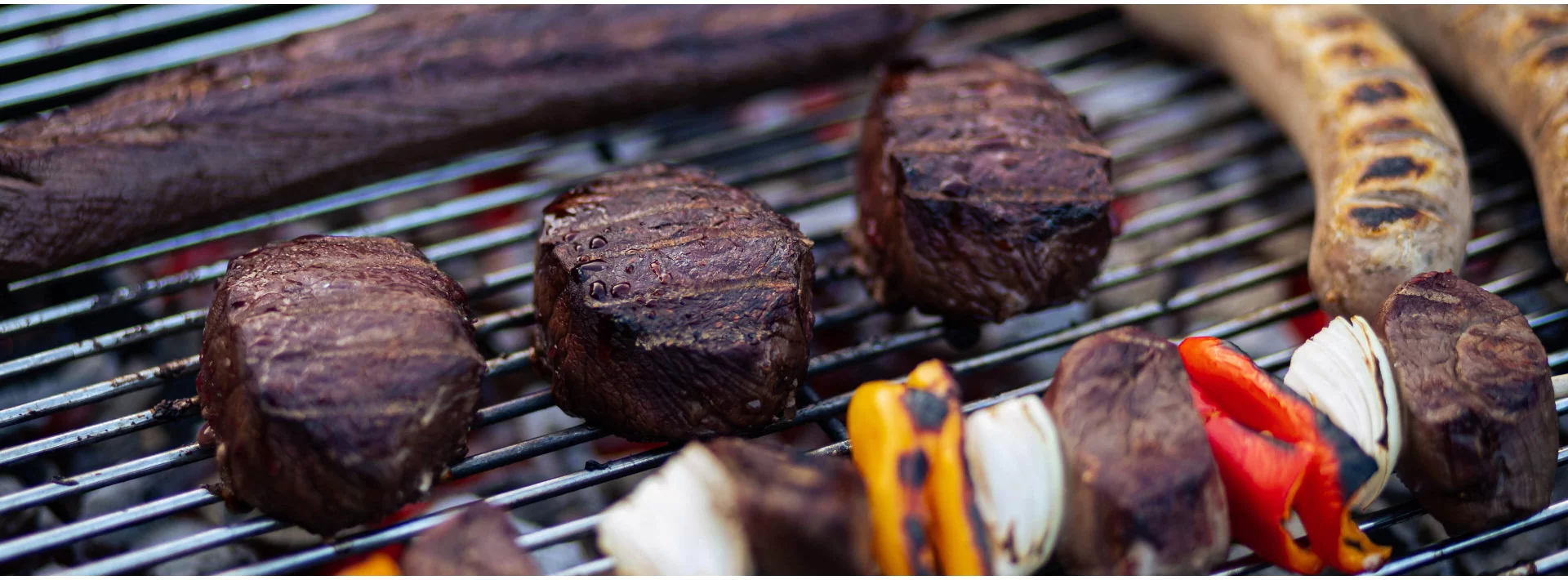 Wildfleisch-Medaillons, Wildbratwurst und Gemüsespieße auf dem Grill als Kategoriebanner