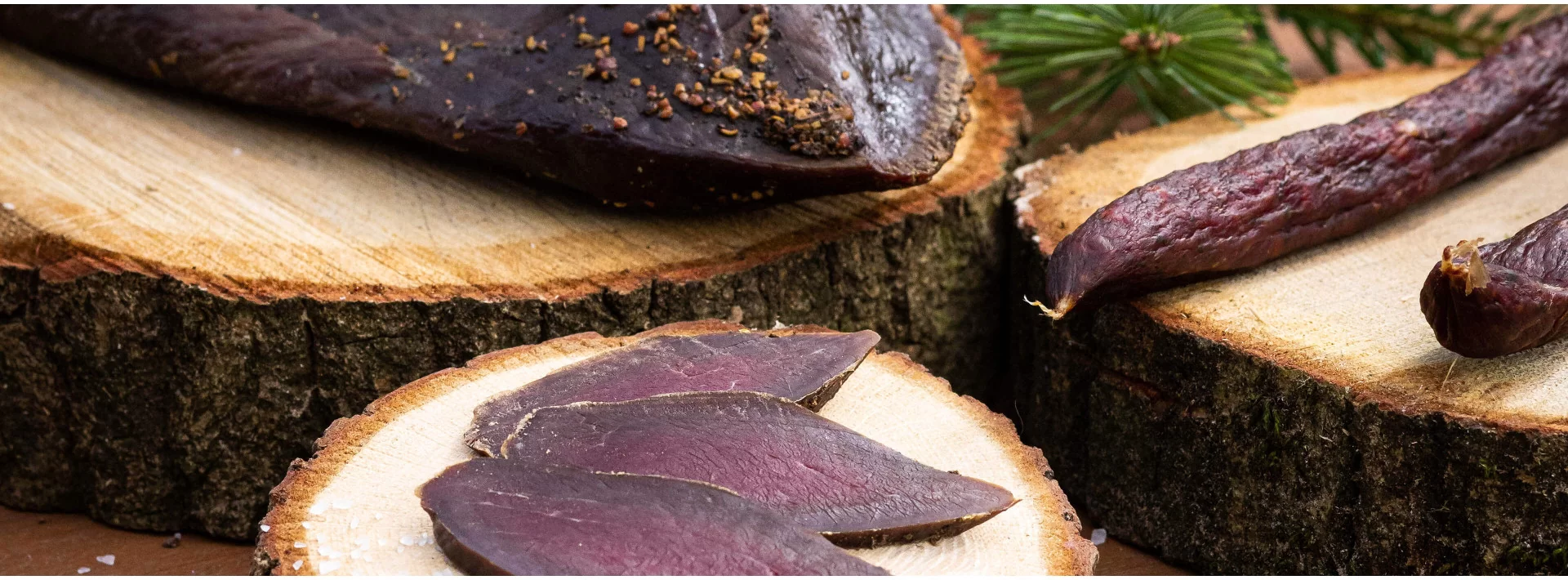 Aufgeschnittene Wildsalami auf Holz im Banner der Wildsalami-Kategorie