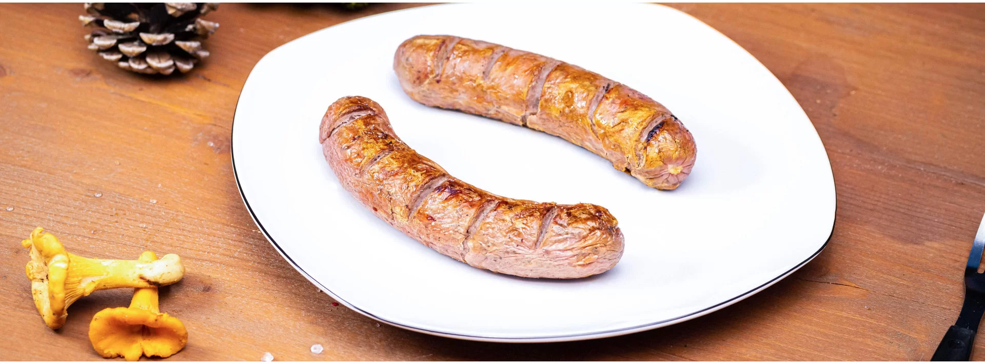 Gebratene Wildbratwürste auf einem Teller im Banner der Wildbratwurst-Kategorie