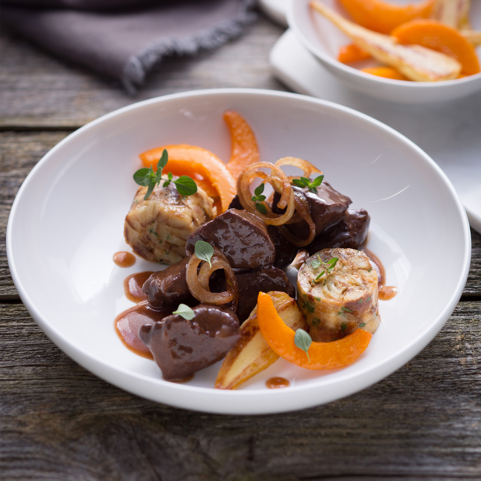 Hirsch-Böfflamott in dunkler Rotweinsauce mit Semmelknödelscheiben, Karotten und Zwiebelringen