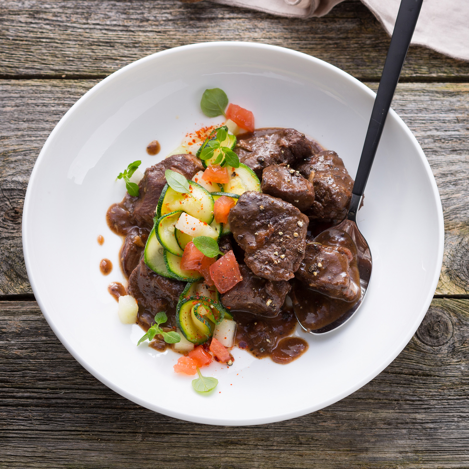 Hirschtopf Peposo mit Tomatenwürfeln, Zucchini, Basilikum und dunkler Rotweinsauce