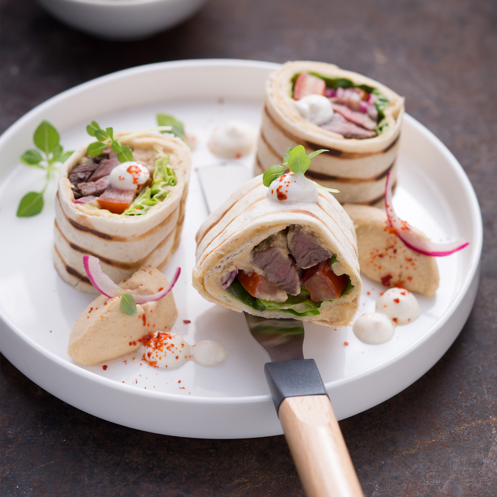 Tortilla-Wraps mit Harissa-Hirschmedaillons, Hummus, roten Zwiebeln und Salat