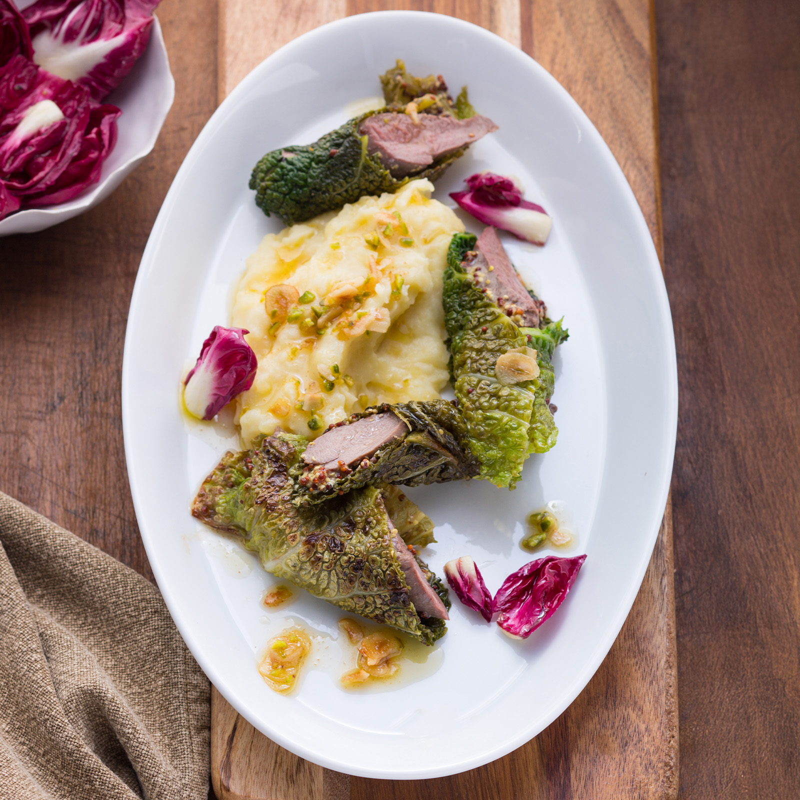 Rehfiletröllchen im Wirsingmantel auf Kartoffelpüree mit gehackten Pistazien und Radicchio