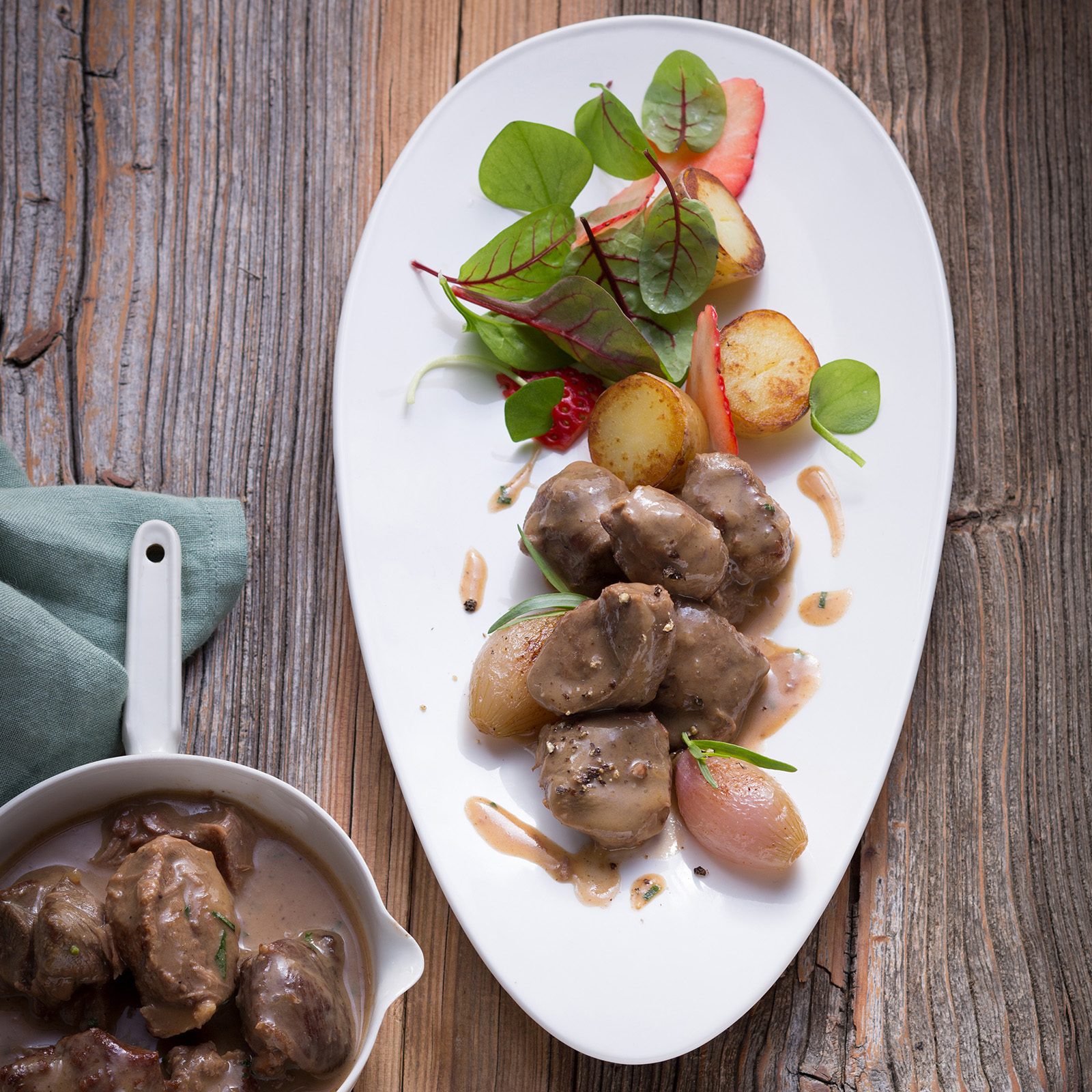 Rehragout mit glasierten Schalotten in heller Rahmsauce, dazu Röstkartoffeln und frischer Blattsalat
