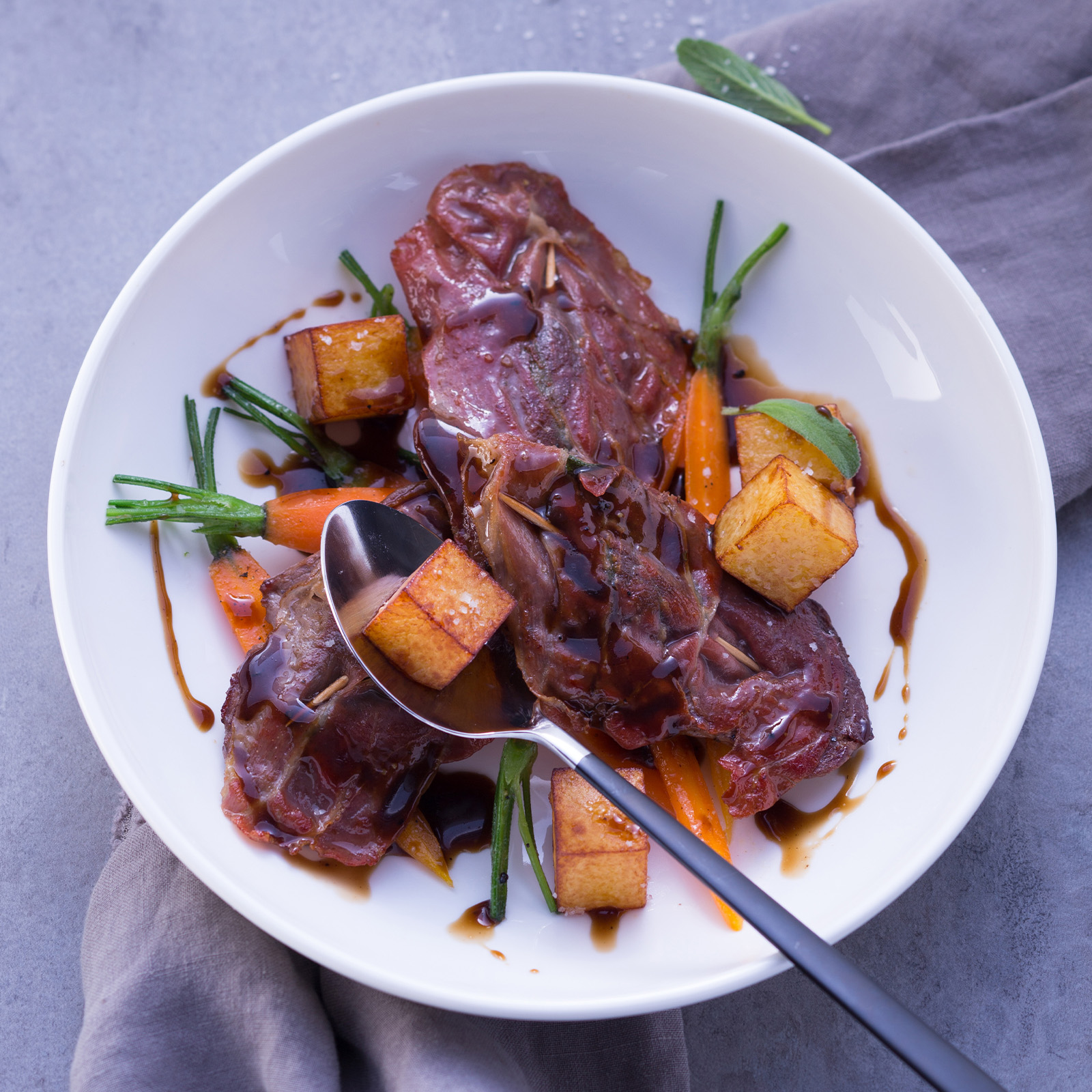 Saltimbocca vom Reh mit Parmaschinken und Salbei, dazu glasierte Babymöhren, Kartoffelwürfel und dunkle Sauce