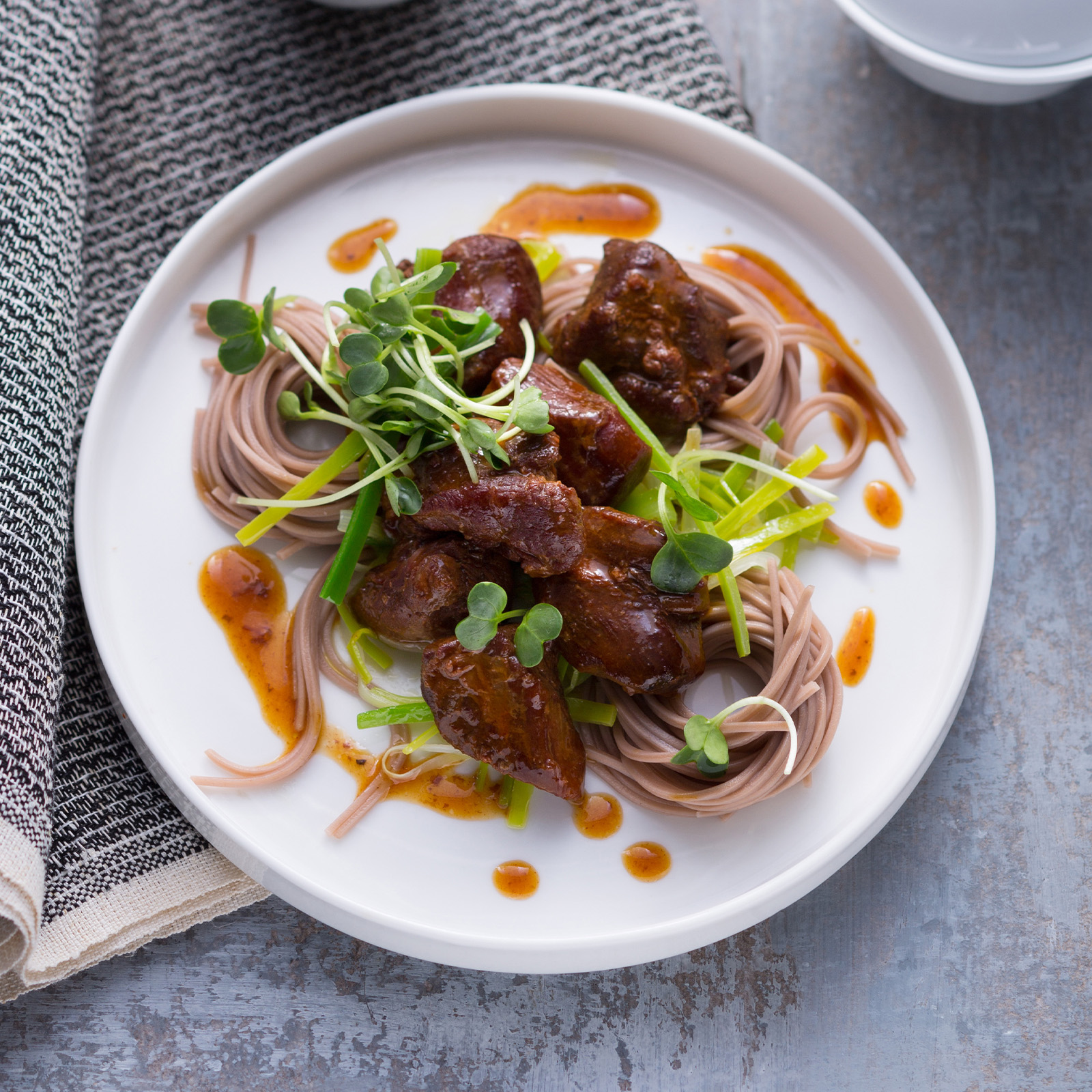 Wildschweinschmortopf Cashu mit Asia-Nudeln, Frühlingszwiebeln und Daikon-Kresse