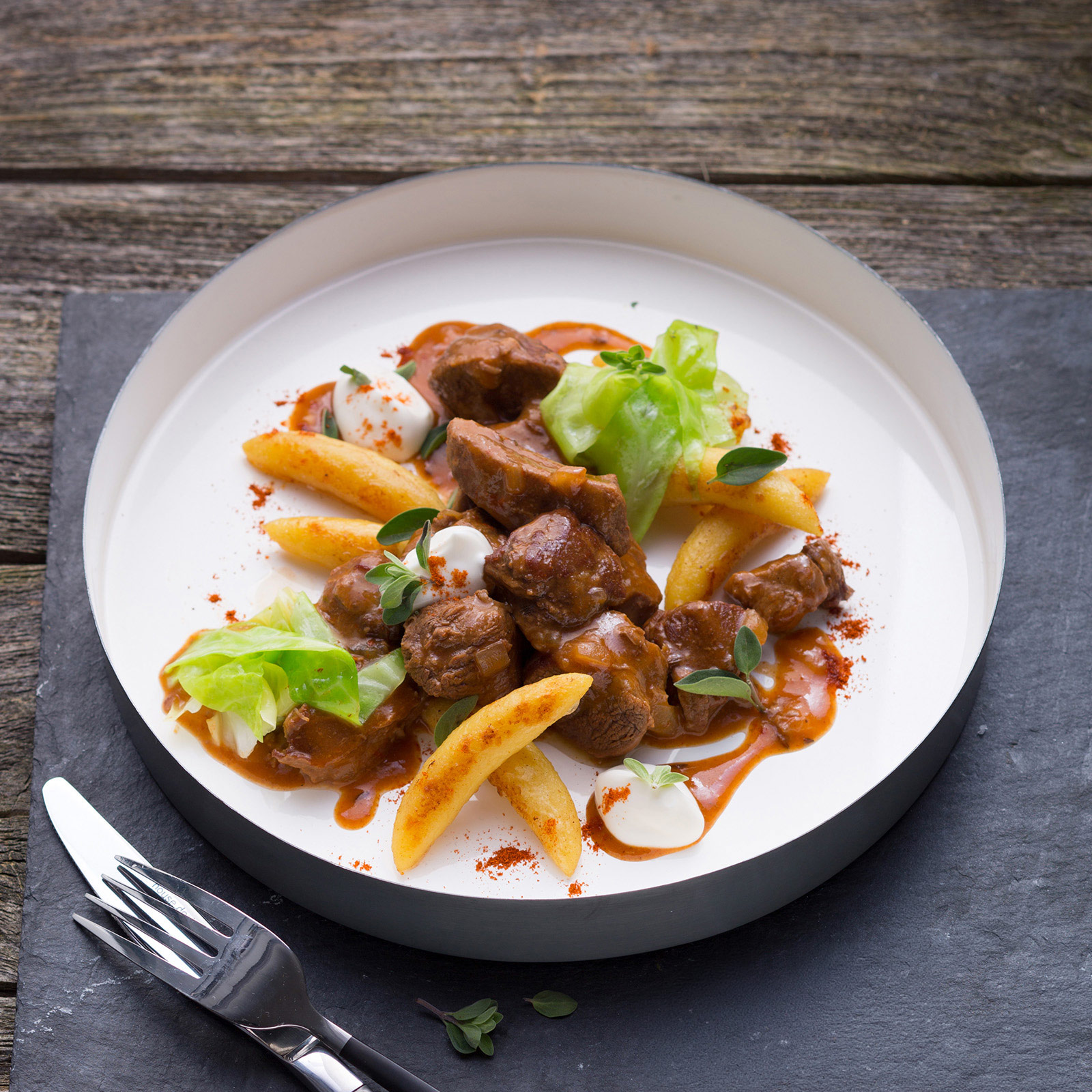 Wildschweingulasch in Paprikasauce mit Schupfnudeln, Spitzkohl, Majoran und Sauerrahm