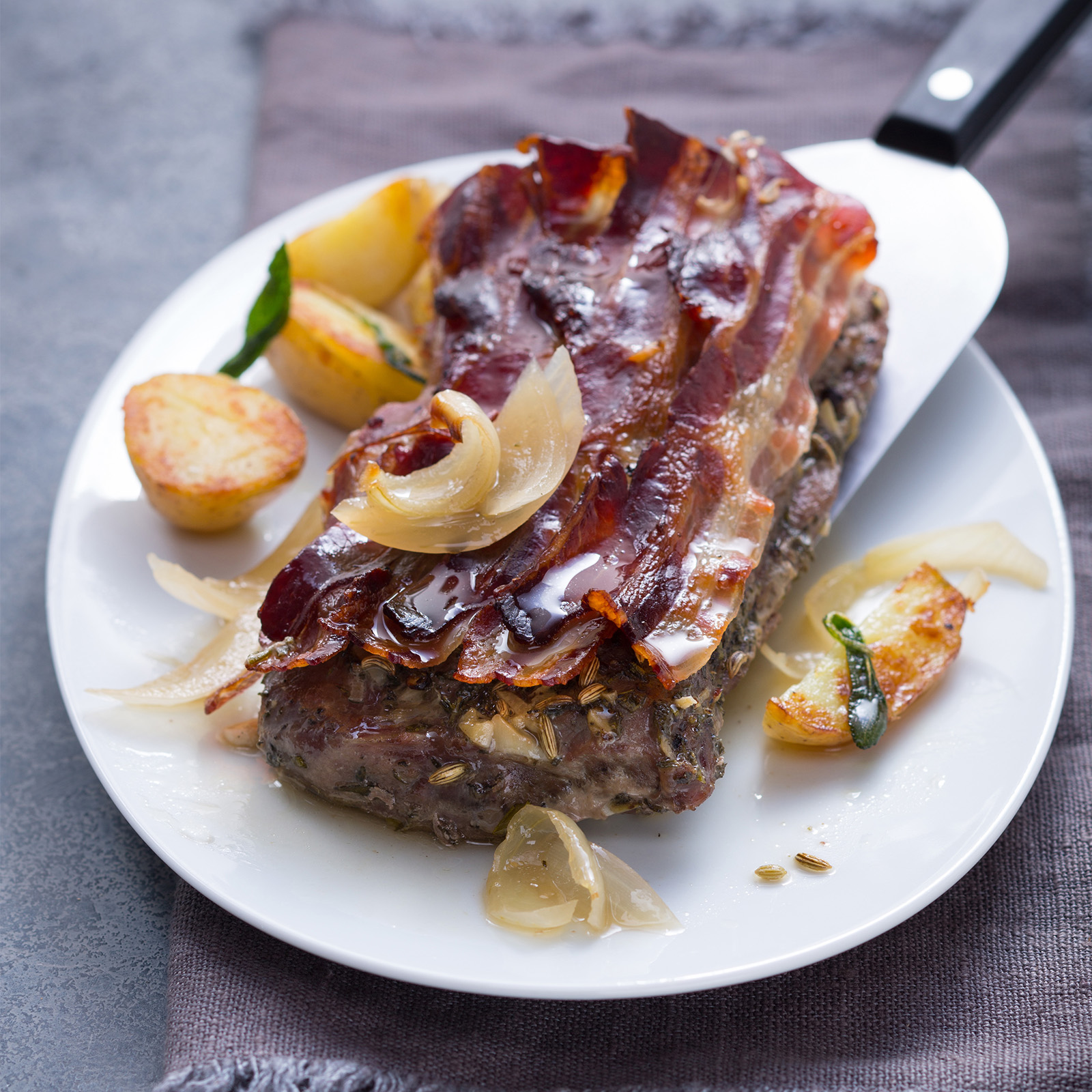 Wildschweinbraten alla Fiorentina im knusprigen Pancetta-Mantel mit Fenchelsamen, glasierten Zwiebeln und Röstkartoffeln