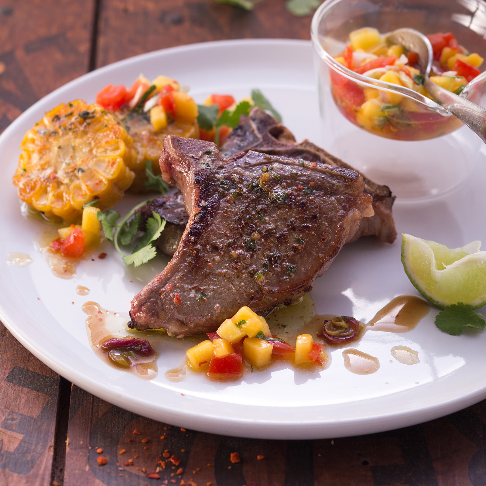Kreolisches Wildschweinkotelett mit Maisküchlein, buntem Paprika-Salsa und Limettenspalte