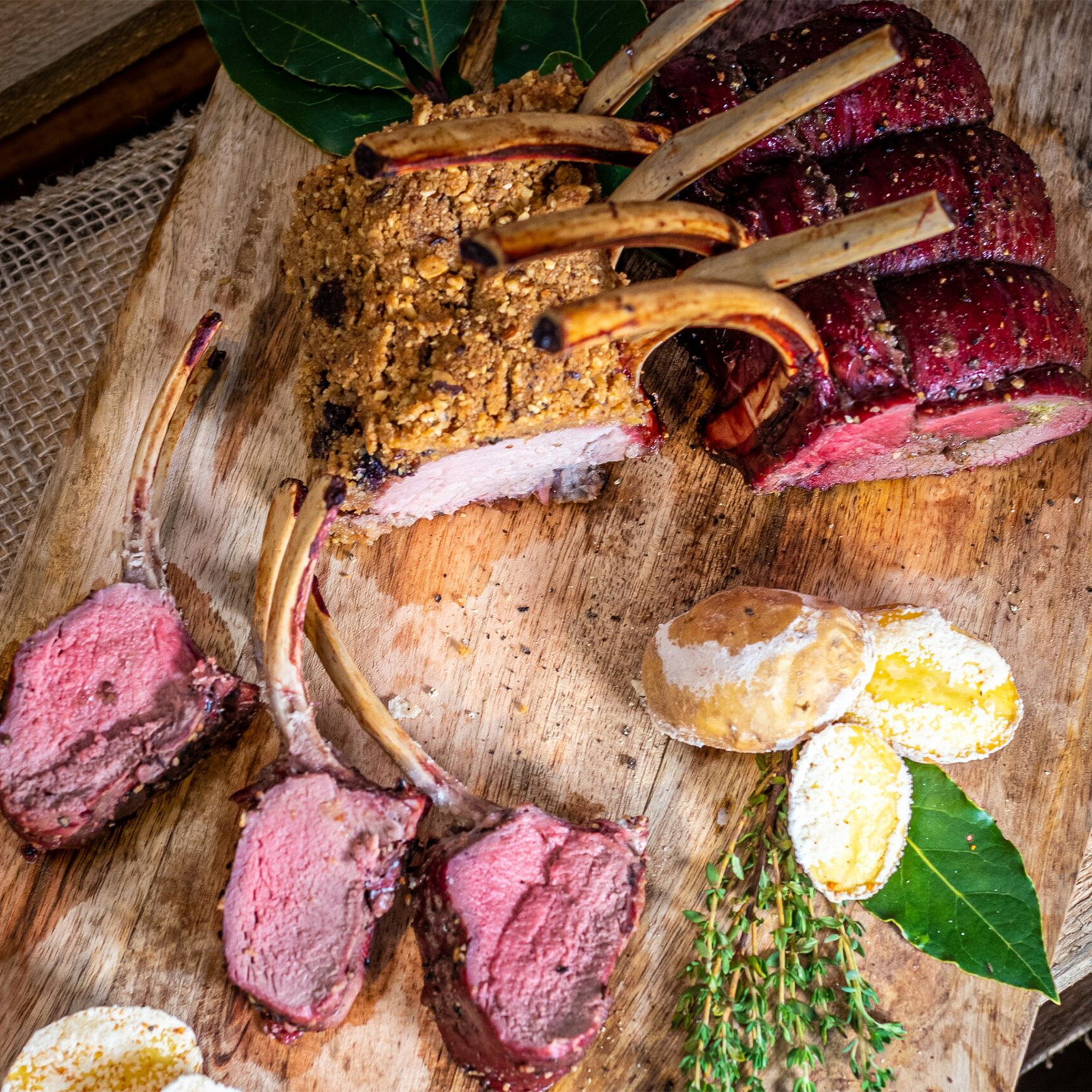 Zur Krone gebundenes Wildkarree mit Kräuterkruste auf einem Holzbrett